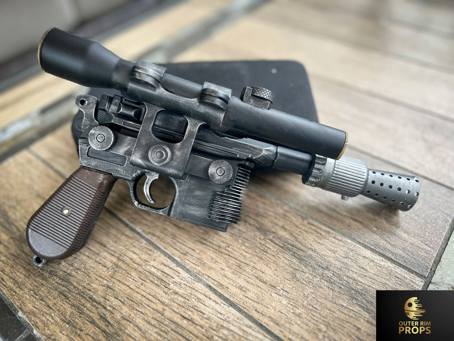 Weathered DL-44 Han Solo blaster replica with scope and detailed prop elements on wood background